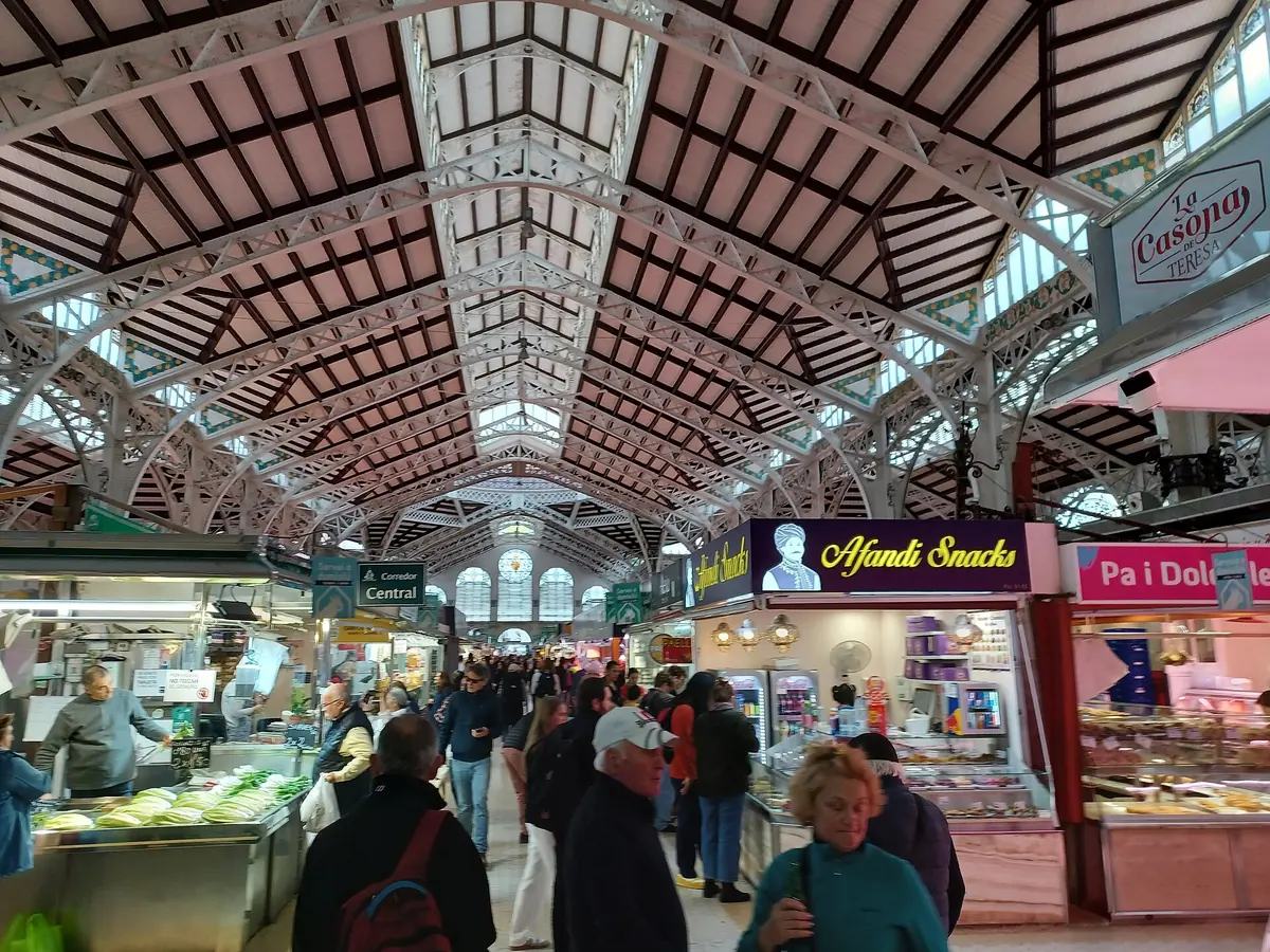 The glass-and-steel roof of the Central Market in Valencia over busy food stalls and shoppers